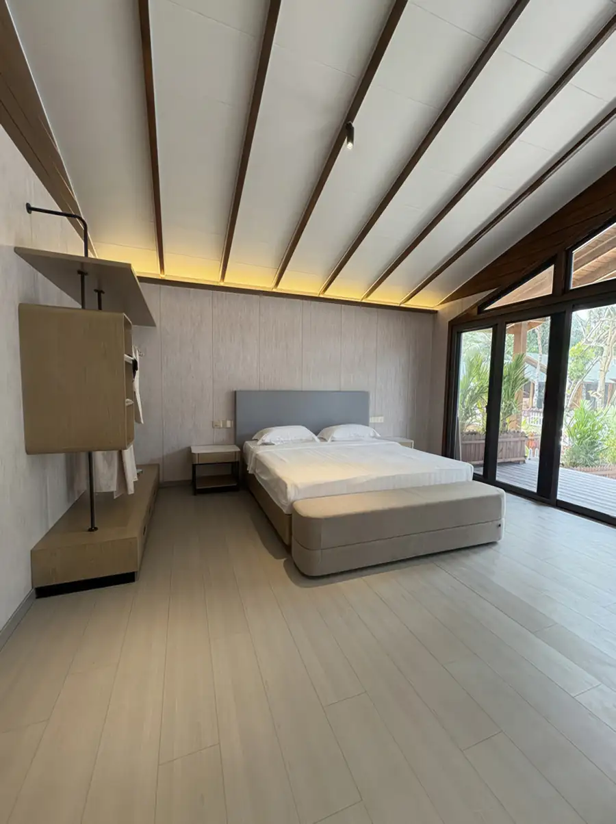 A modern bedroom at Doris Mataking Resort featuring a king bed facing panoramic glass doors with direct access to the private balcony