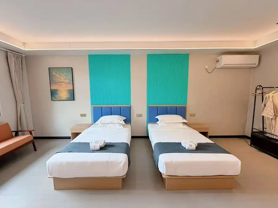 A contemporary bedroom at Doris Mataking Resort with twin beds with turquoise accents and warm wooden flooring