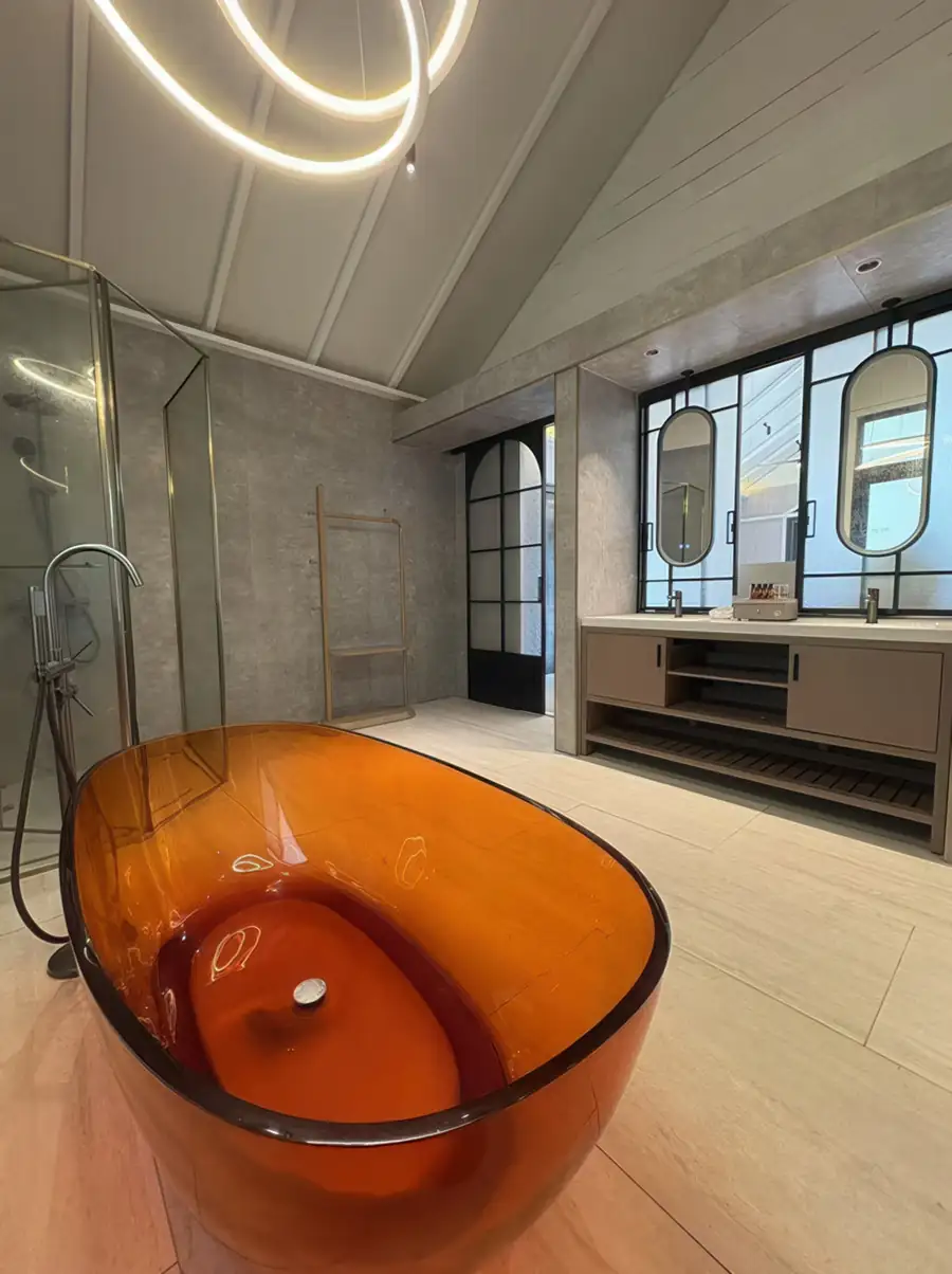 A luxurious bathroom at Doris Mataking Resort featuring a unique transparent amber resin bathtub and modern dual vanity