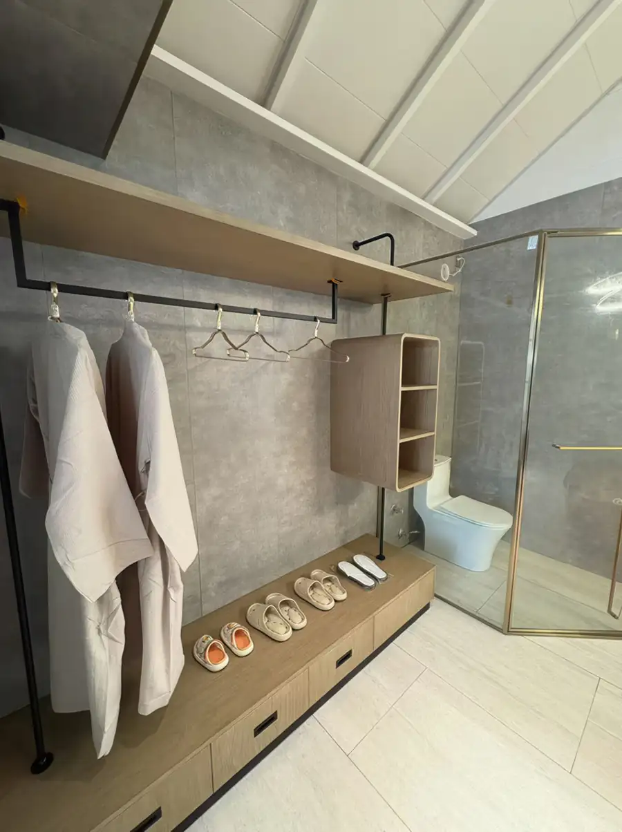 A modern bathroom at Doris Mataking Resort with a sleek dark vanity, round mirror and electric shower stall