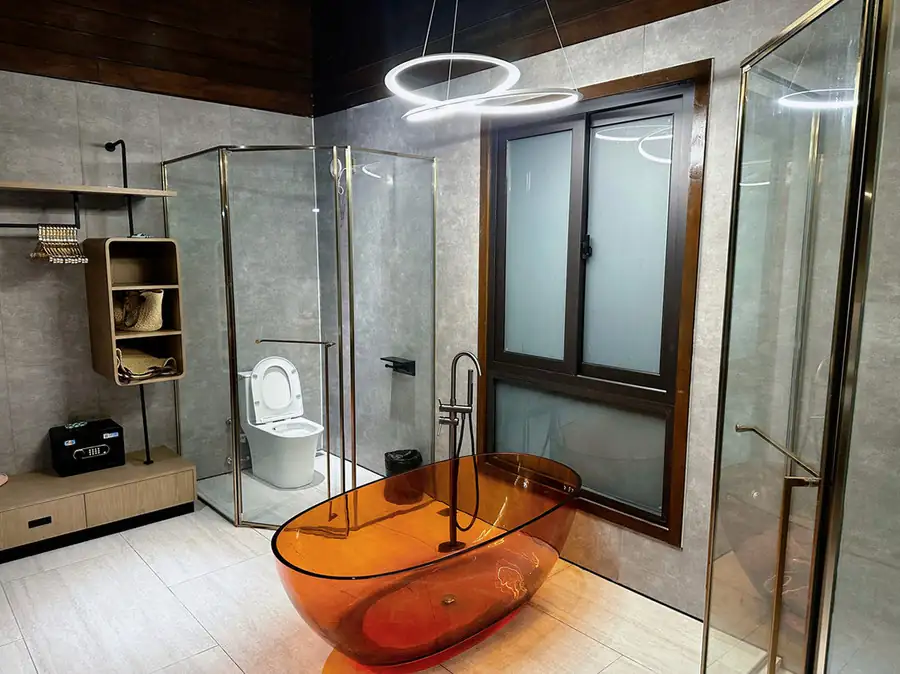 A VIP suite bathroom at Doris Mataking Resort featuring an amber resin tub, glass-walled toilet enclosure and open wardrobe
