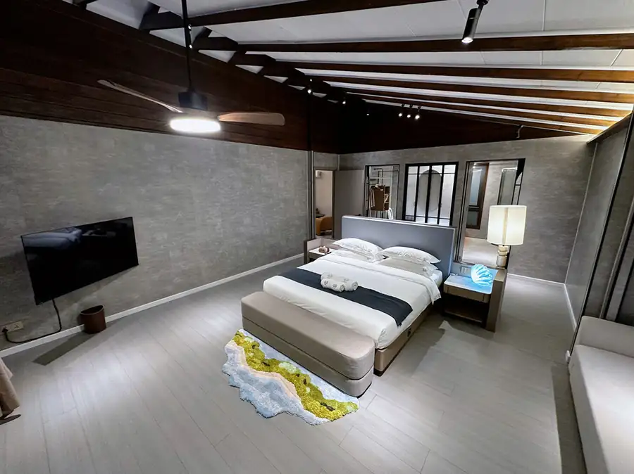 A magnificent VIP bedroom at Doris Mataking Resort showcasing a large bed facing a mounted TV with vaulted ceilings and authentic wooden floors
