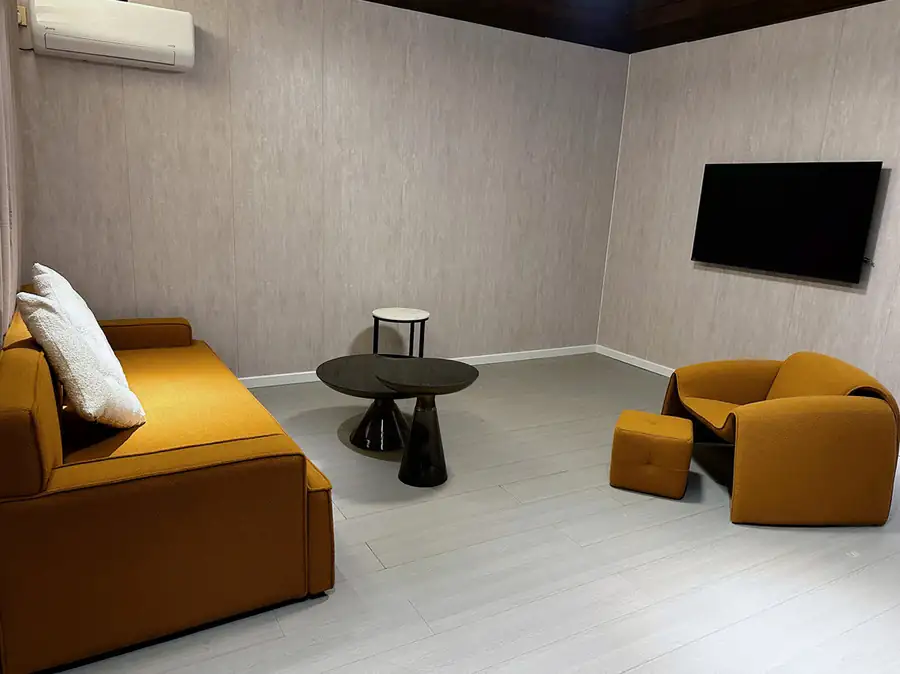 A modern living area at Doris Mataking Resort featuring a plush ochre sofa, designer coffee tables and gleaming timber floors